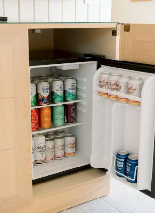 An open mini refrigerator stocked with a variety of canned beverages, including drinks on the shelves and in the door compartments.